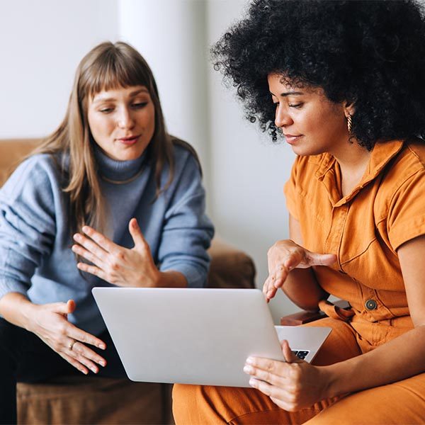 two women discussing business using a laptop